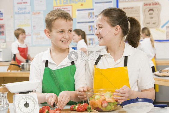 准备切片水果的男女生和女学生头发外表孩子们家电厨师器具孩子班级男孩们浆果图片