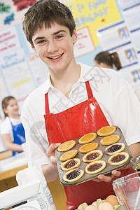 男学生在烹饪课中拿着一盘果塔板的男学生图片