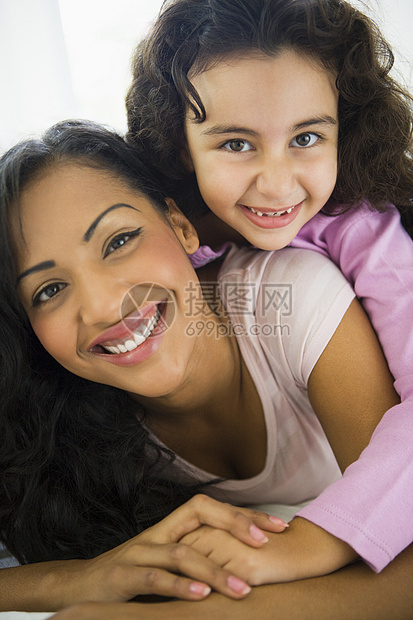 在客厅中的母亲和女儿拥抱和微笑高关键选择性重点小学生女孩镜头女儿们小学孩子们情感女性特写家庭图片
