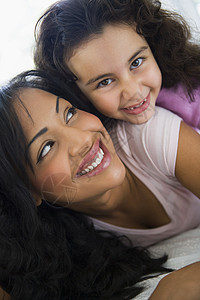 在客厅中的母亲和女儿拥抱和微笑高关键选择性重点小学生亲热女性幸福成人成年人女儿们感情年龄情感图片