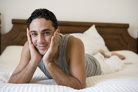 男人在床上放松 在卧室微笑选择性焦点焦距镜头水平成年人成人视角幸福房屋情感房子图片