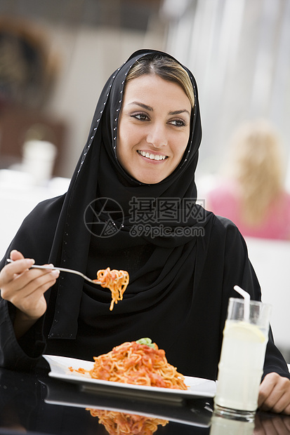 餐厅妇女吃意大利面和微笑选择性焦点的女人种饮料衣服成年人焦距情感情绪食品食物成人图片