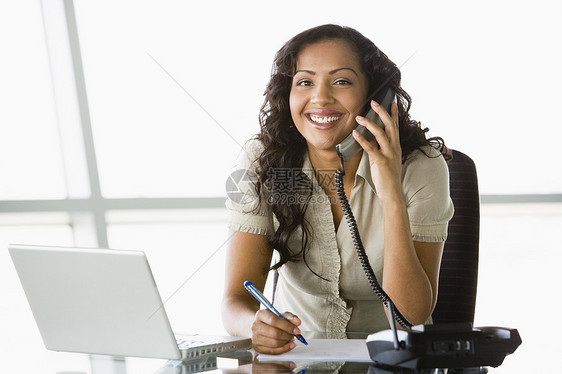 使用膝上型电脑微笑电话高键选择性重点担任办公职位的女商务人士桌子窗户商界沟通商业通讯商务成年人生意人女性图片