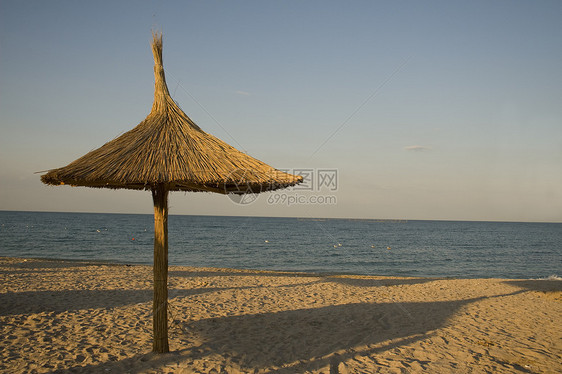 沙滩上划成单毛的雨伞旅游海岸线芦苇蓝色孤独享受木头岛屿海岸阴影图片