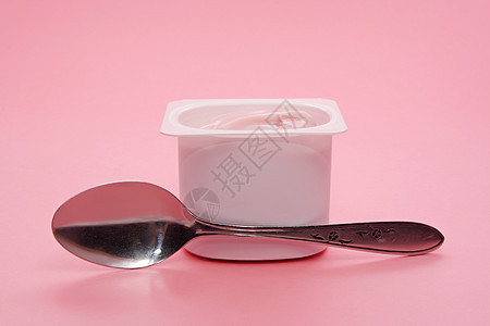 塑料容器中的酸奶粉色食物杯子营养勺子小吃白色甜点奶制品饮食背景图片