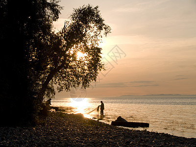 湖面日落血管成人太阳活动渔夫男人场景海滩卵石假期图片