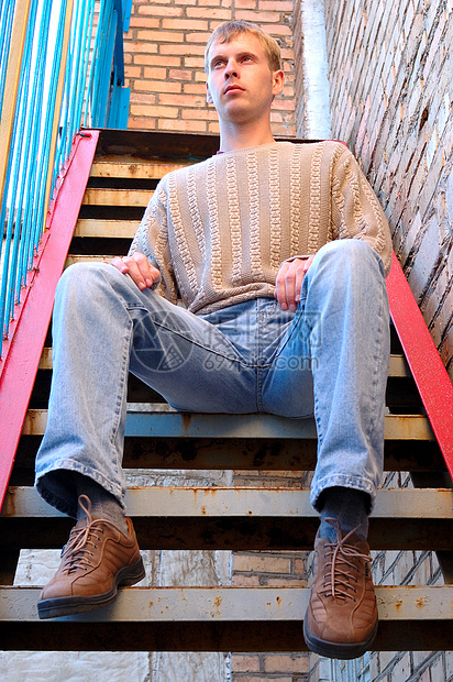 年轻时尚的人坐在砖墙附近的楼梯上头发浅黄色小鹿橙子蓝色男人脚步鞋类金发女郎梯子图片