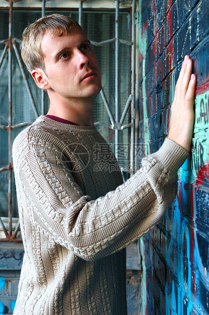 年轻时尚的人站在涂鸦砖墙附近毛衣蓝色牛仔裤衣服浅黄色男人橙子小鹿金发女郎头发图片
