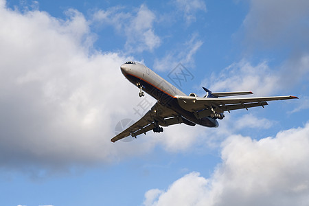 客机降落在蓝天上 有云彩背景图片