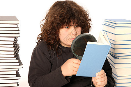 男孩子用透镜阅读一本书百科瞳孔童年专注考试工作学生文学学校测试图片