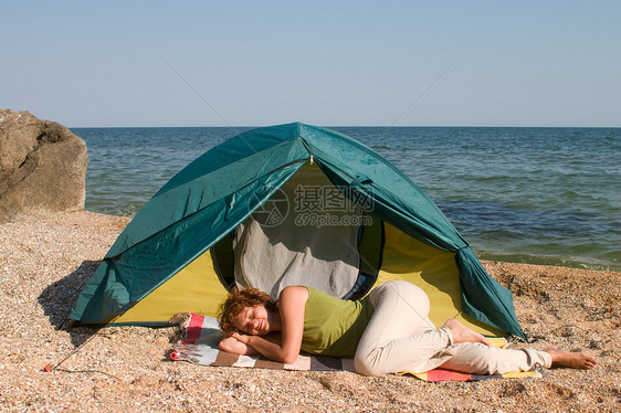 妇女睡在海边帐篷附近图片