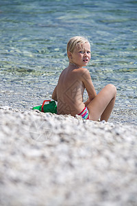 海滩上的女孩波浪头发孩子晴天玩具眼睛海洋童年喜悦乐趣图片