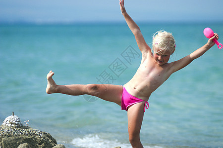 海滩上的女孩金发女郎喜悦童年玩具蓝色微笑海洋波浪孩子天空背景图片