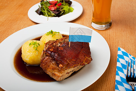 巴伐利亚烤猪肉菜和土豆蓝光旗帜饺子敷料饮食营养桌子韭菜餐巾啤酒图片