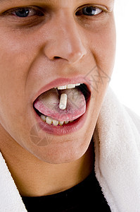 青年男子用药丸在他的舌头上背景图片
