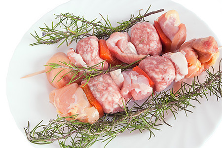 带迷迭香的猪肉烤肉串红色烤串胡椒绿色牛扒木炭白色蔬菜香肠盘子图片