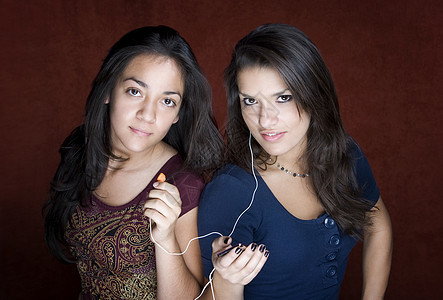 两名青年女听音乐的妇女朋友娱乐女孩姐姐乐趣音乐黑发金属电子微笑图片