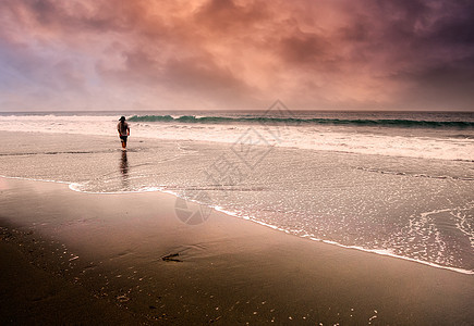 孤独的男子在海滩上行走图片