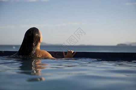 女人在游泳池里放松禅意女性生活方式游泳衣成人日光浴反射享受蓝色休闲图片