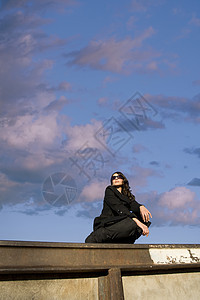 漂亮西班牙裔妇女太阳镜金属天空光束外套眼镜女性黑发背景图片