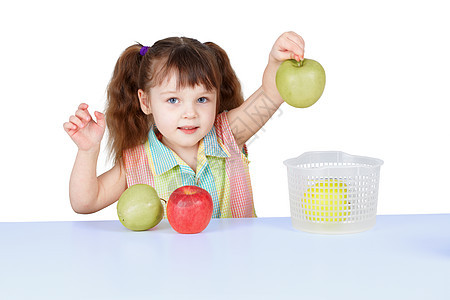小女孩玩绿苹果 坐在桌边的桌子上图片