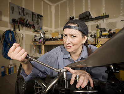 西班牙裔女性技工c运输微笑车库能力力量引擎菜刀扳手摩托车螺栓图片