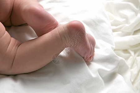 长着腿躺在白毯上的小可爱新生婴儿图片