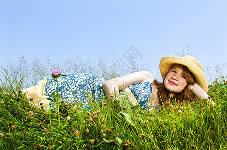 年轻女孩躺在草原上稻草花朵女孩们天空裙子帽子假期野花青少年草帽图片