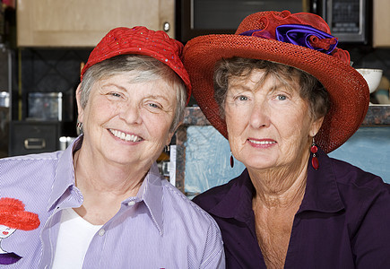 两名身戴红帽子的高级妇女老年女性退休帽子红色女士朋友俱乐部灰色快乐背景图片