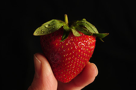 两根手指之间的单草莓夹在一起图片