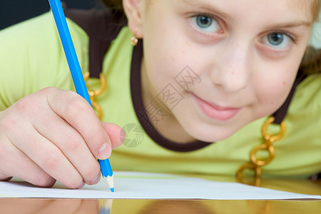 女孩拿着蓝铅笔照片叶子微笑绘画水平女学生桌子写字桌绿色棕色图片