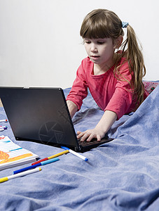 7岁的可爱小女孩玩电脑游戏的7岁女孩享受帮助笔记本技术学习智力动机电脑天赋网络图片