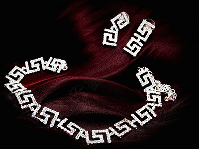 红织物上的项链耳环奢华丝绸首饰布料宝藏热情石头魅力宝石珠宝图片