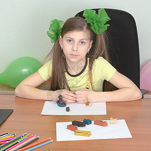 女孩坐在有塑料的桌子上女学生相似度娘娘腔叶子铅笔照片绿色橡皮泥写字桌黄色图片