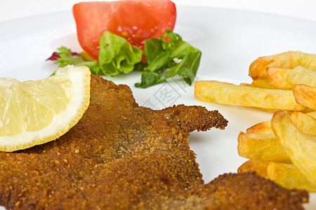 盘子上的雪梨肉排的细细细节柠檬猪肉薯条叶子棕色午餐面包屑食物图片