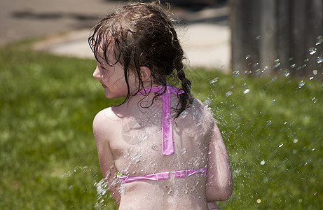 女孩在水里玩耍活动游泳衣喷涂休闲小女孩比基尼女孩们享受家庭生活洒水器图片