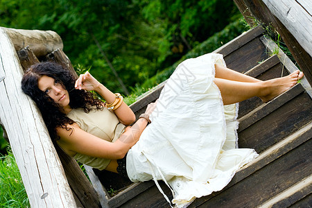 妇女坐在木制楼梯上木头白色孤独女士黑发头发脚步女孩公园树木图片