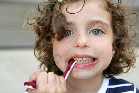 小女孩吃甜糖 面脸脏生日小吃蓝色嘴唇乐趣喜悦孩子青年童年牙齿图片