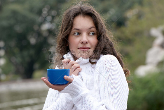 这名年轻女子的肖像 一杯户外热饮的杯子咖啡毛衣女士皮肤肤色人像楷模手指夹克蒸汽图片