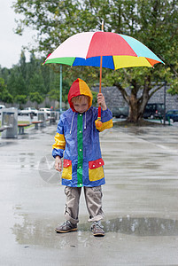 带着雨伞的男孩站在雨下童年俏皮男性防水男生水池雨衣表情孩子乐趣图片