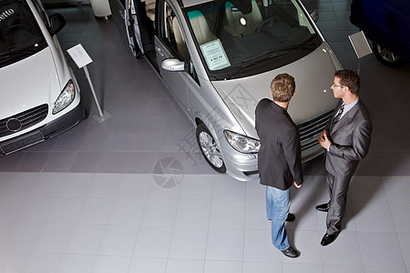 汽车销售员向客户解释汽车特写奢华展览会水平方式展示优雅顾客职业销售沟通图片
