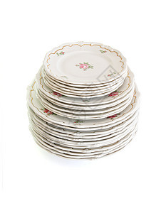 高堆的白色餐盘和配鲜花和大浪圆边隔绝的碟子图片