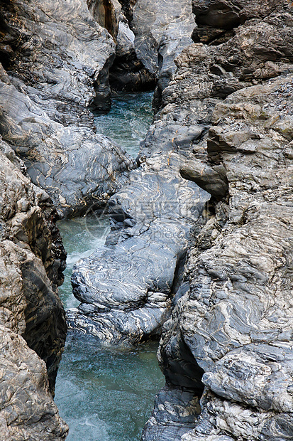 在阿尔卑斯山脉的蓝条状岩石之间 近距离渗出山洪流图片