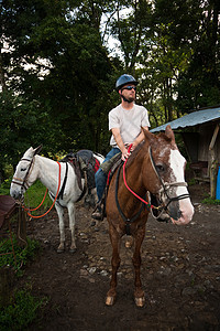 在哥斯达黎加骑马的欧洲人或美国人男子马背旅行眼镜骑士森林头盔牧场丛林动物哺乳动物图片