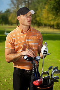 年轻人站在高尔夫球袋旁站着收腰前景对象高尔夫金属服装运动手套休闲沉思图片