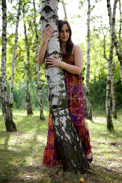 年轻女子在公园拥抱树的肖像图片
