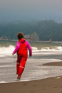 身着红雨衣的年轻女孩在美国瓦辛顿海滨红色乐趣雨具辫子女儿海滩姐姐图片