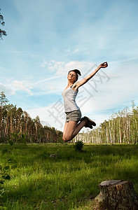 年轻女孩跳到木头和天空上图片