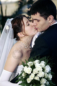 新婚夫妇接吻热情妻子快乐女性成年人日光花朵夫妻花束婚纱背景图片