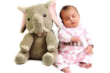 女孩 坐在她旁边和大象玩具睡觉的女婴图片
